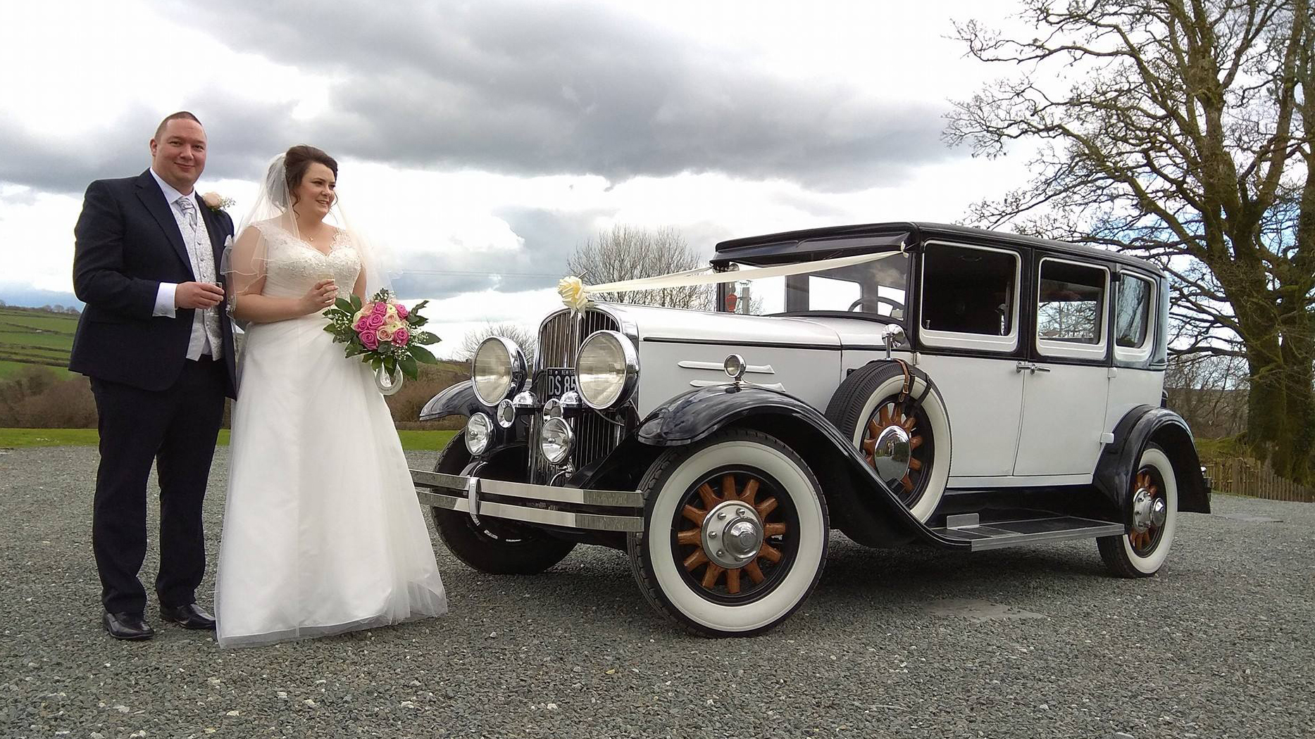 Bride and Groom in front of Vintage Wedding Car decoraqted with ivory ribbons