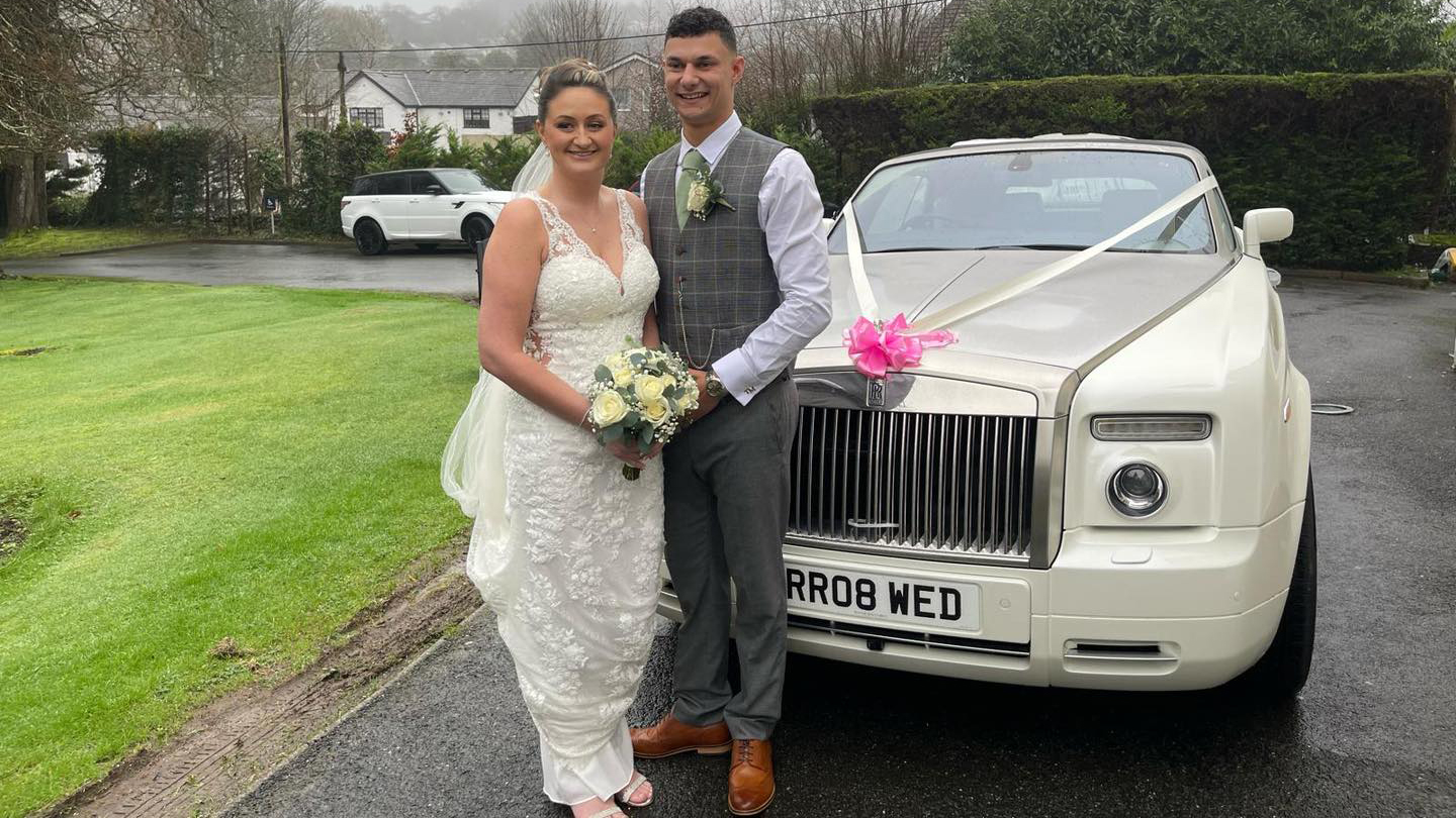 Rolls-Royce Phantom Drophead with bride and groom standing in frotn of the car