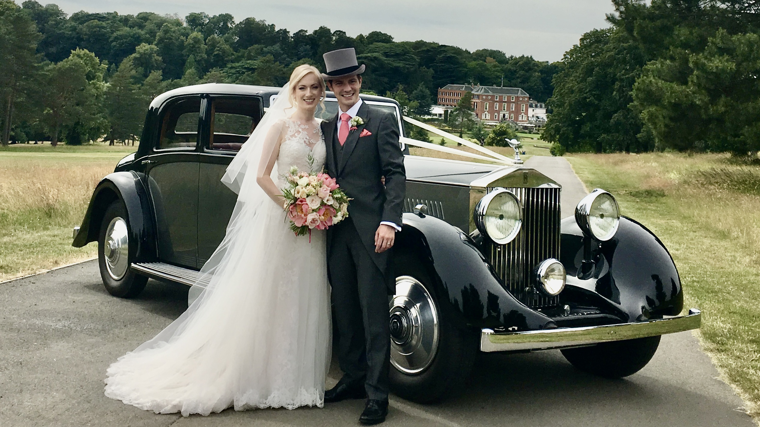 Bride and Groom holding each others in front of the Vintage Rolls-Royce