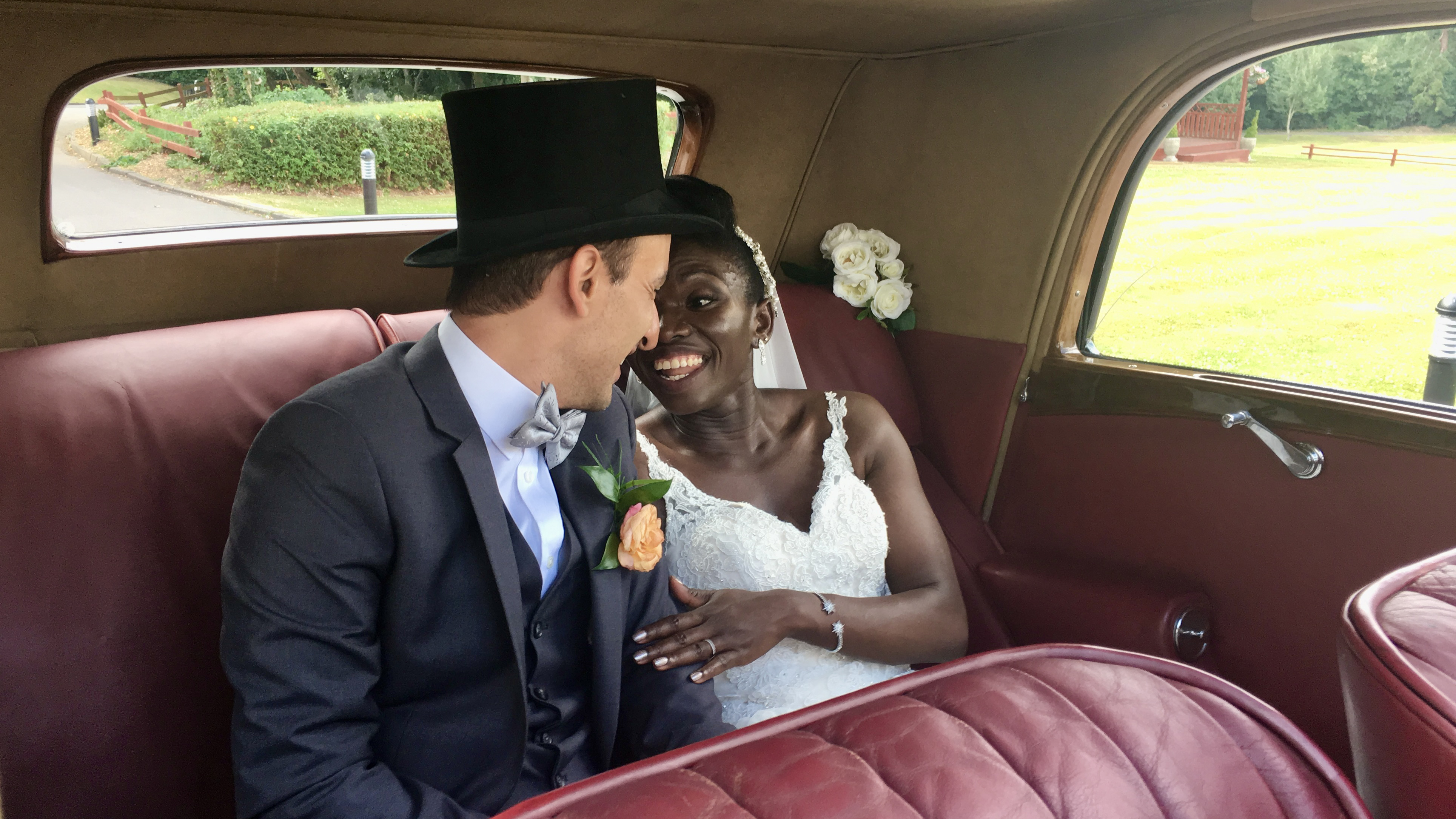 Bride and Groom smiling in the rear seat of vintage car
