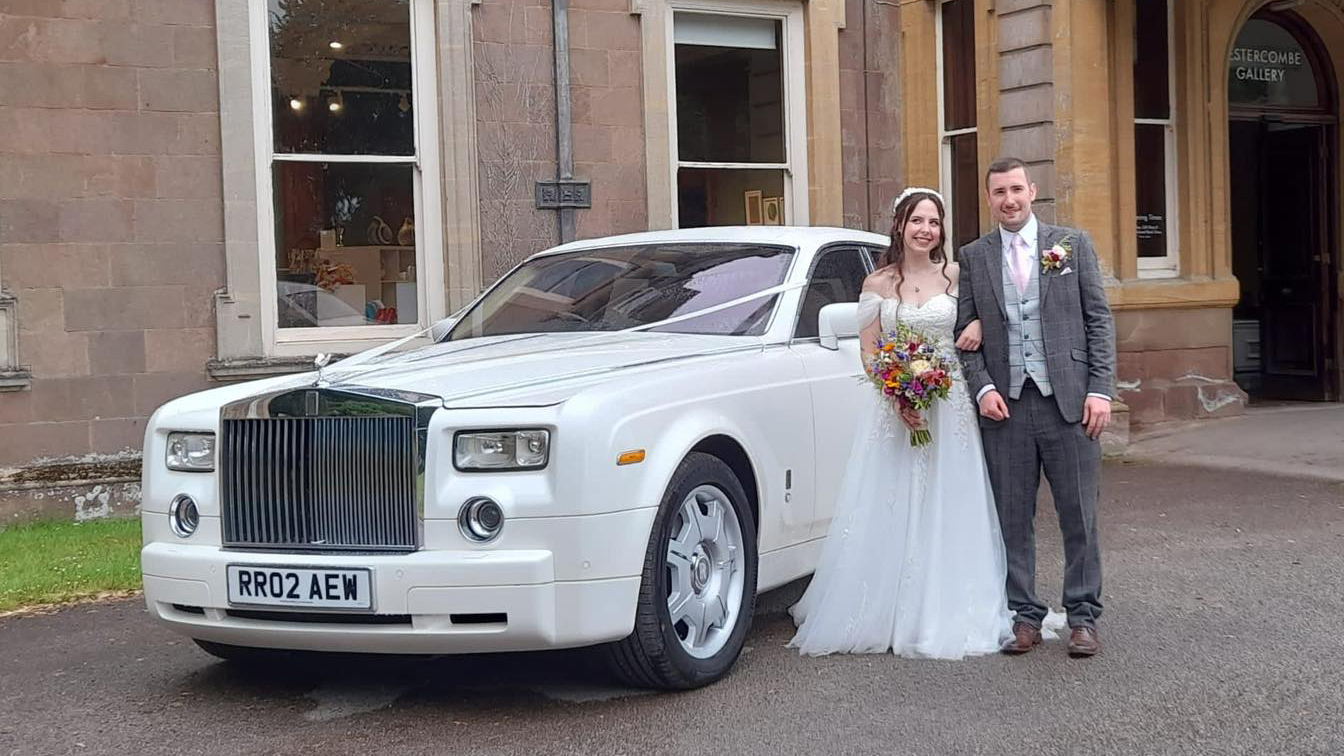 Rolls-Royce Phantom in white in front of a wedding venue with Bride and Groom standing next to the vehicle