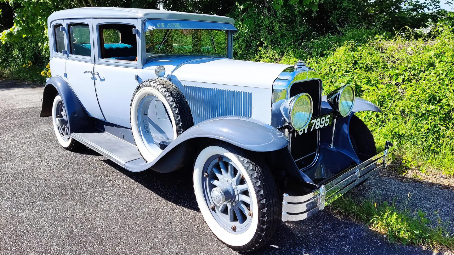 Light Blue vintage Buick Master Sedan parked in front of a green hay