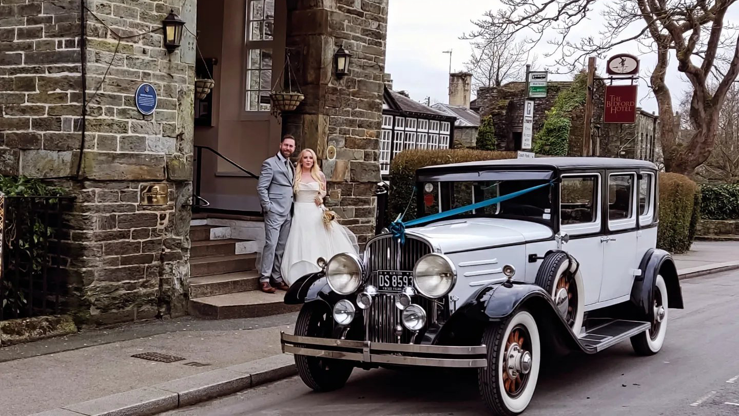 Black & White vintage Frankling wedding car with Bride and Groom in the background