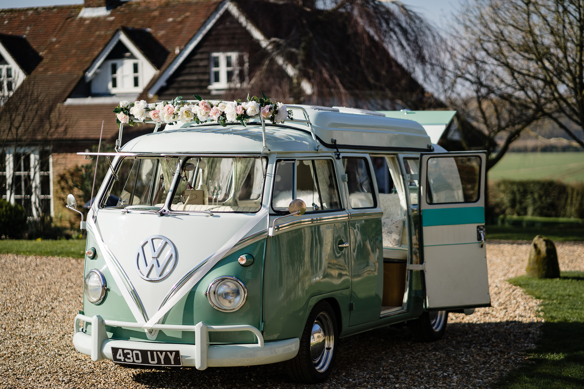 Retro Classic Volkswagen Splitscreen Campervan in two tone White and Pastel Green decorated with White Ribbons on front Bonnet and Wedding Flowers on top