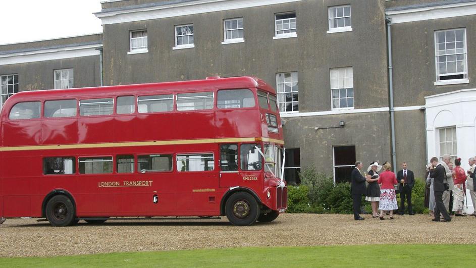 Red Routemaster bus with some wedding guests