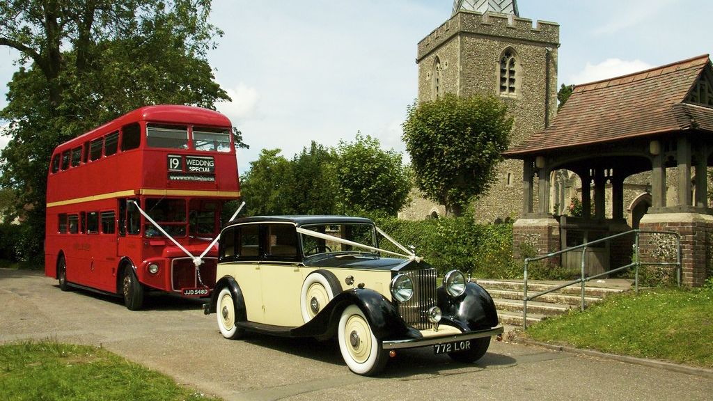 Vintage car followed by a Routemaster Bus with matching white ribbons.