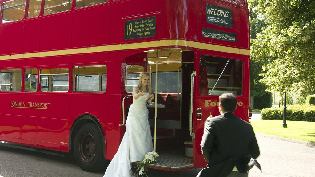 Bride standing on the rear open platform of a Red Routemaster Bus