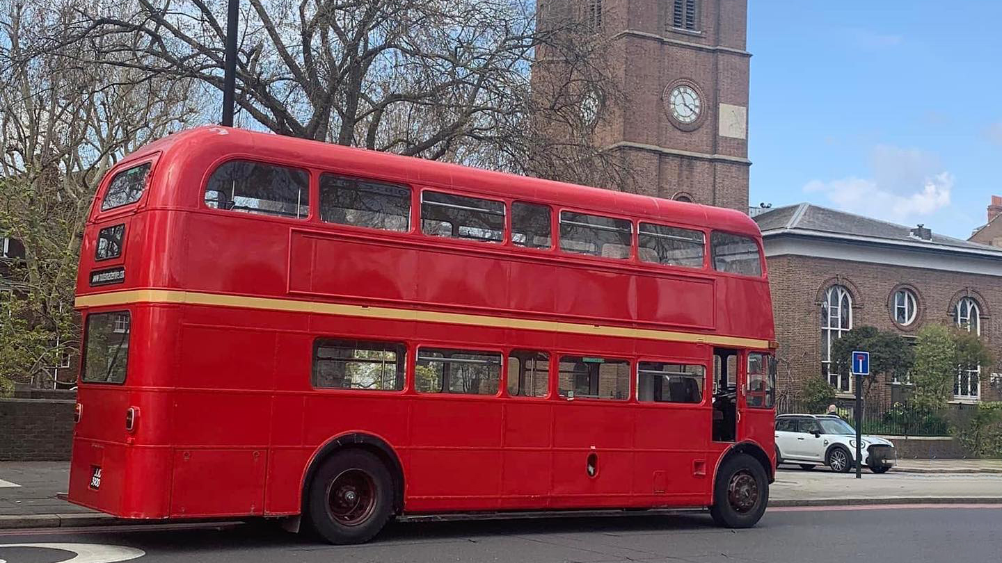 Right side of Red Routemaster bus being driven in the street of London