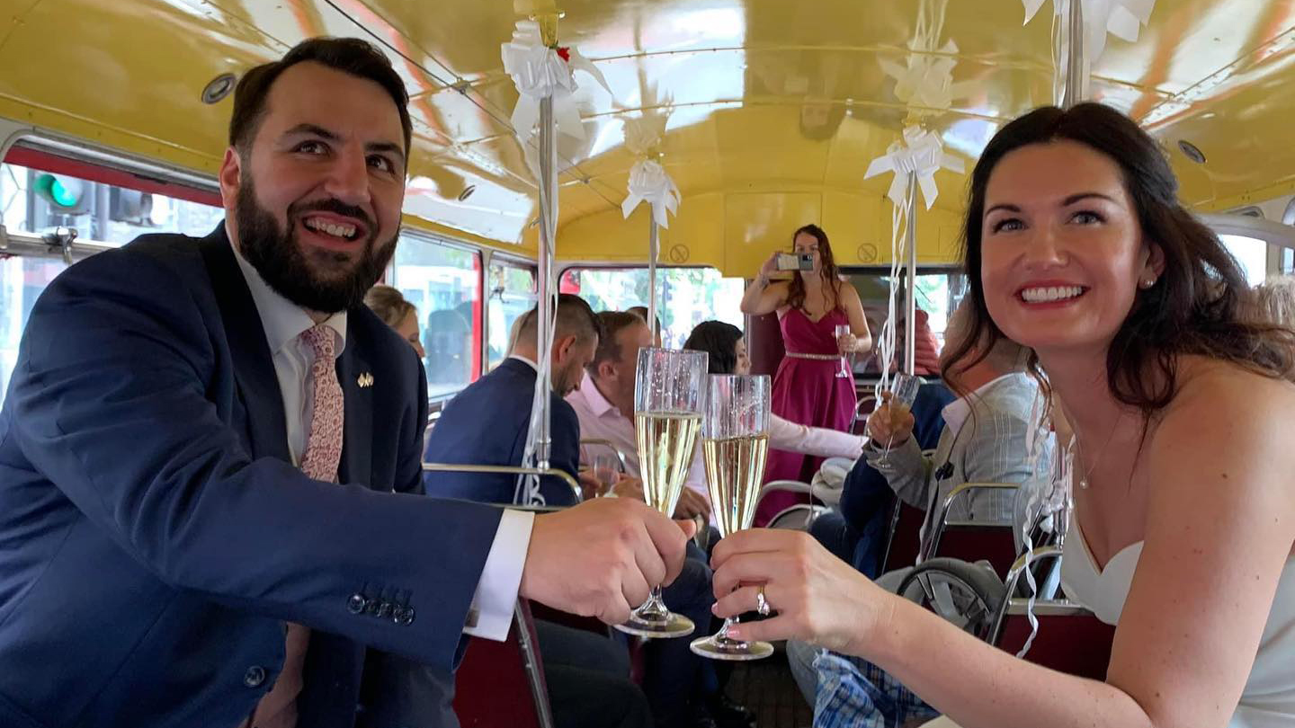 Bride and Groom holding a champagne Glass inside a Routemaster Bus