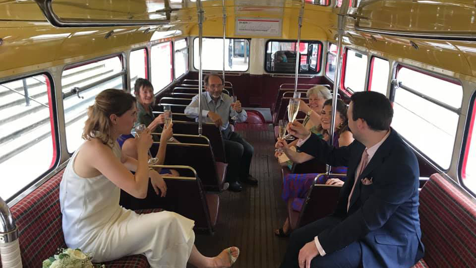 Bride and Groom with their wedding guests seated inside the lower deck of Routemaster bus