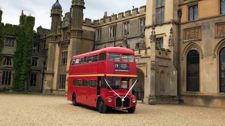 Double Decker Red Routemaster bus with White Ribbons in front of a wedding venue