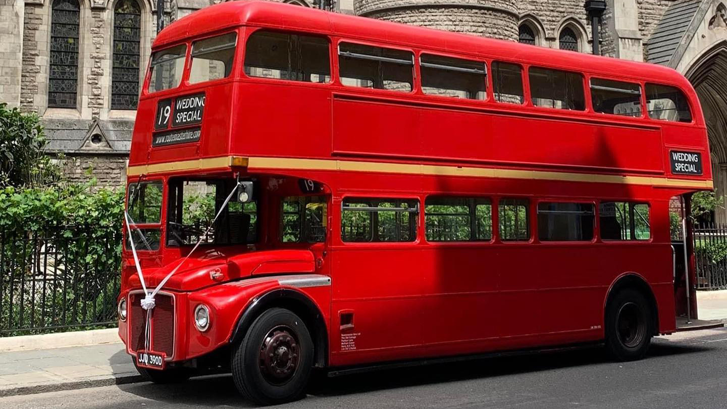 Left Side of Routemaster bus decorated with white ribbons in front of a church