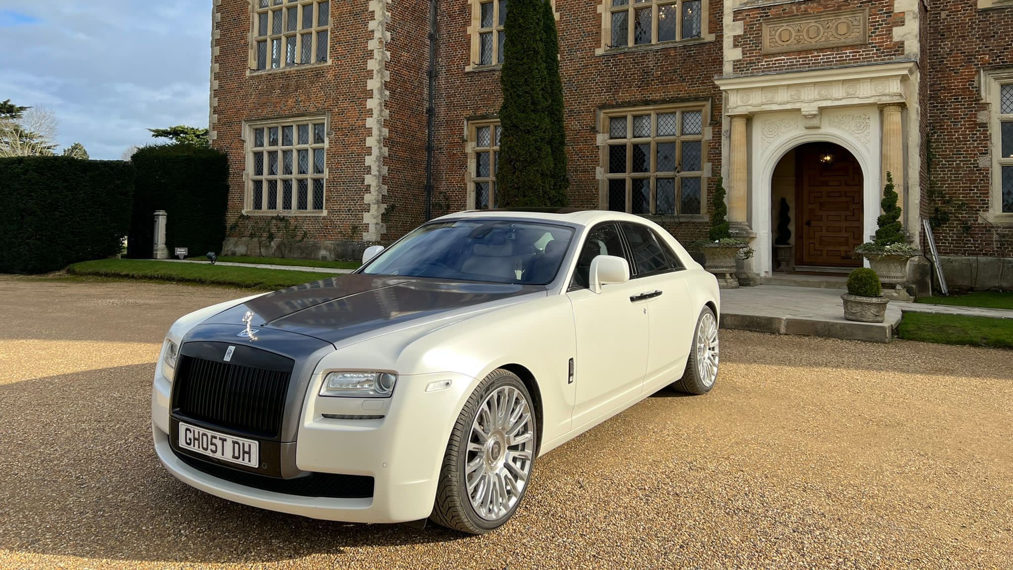 White Rolls-Royce Ghost with silver bonnet parked in front of a wedding venue in Surrey.