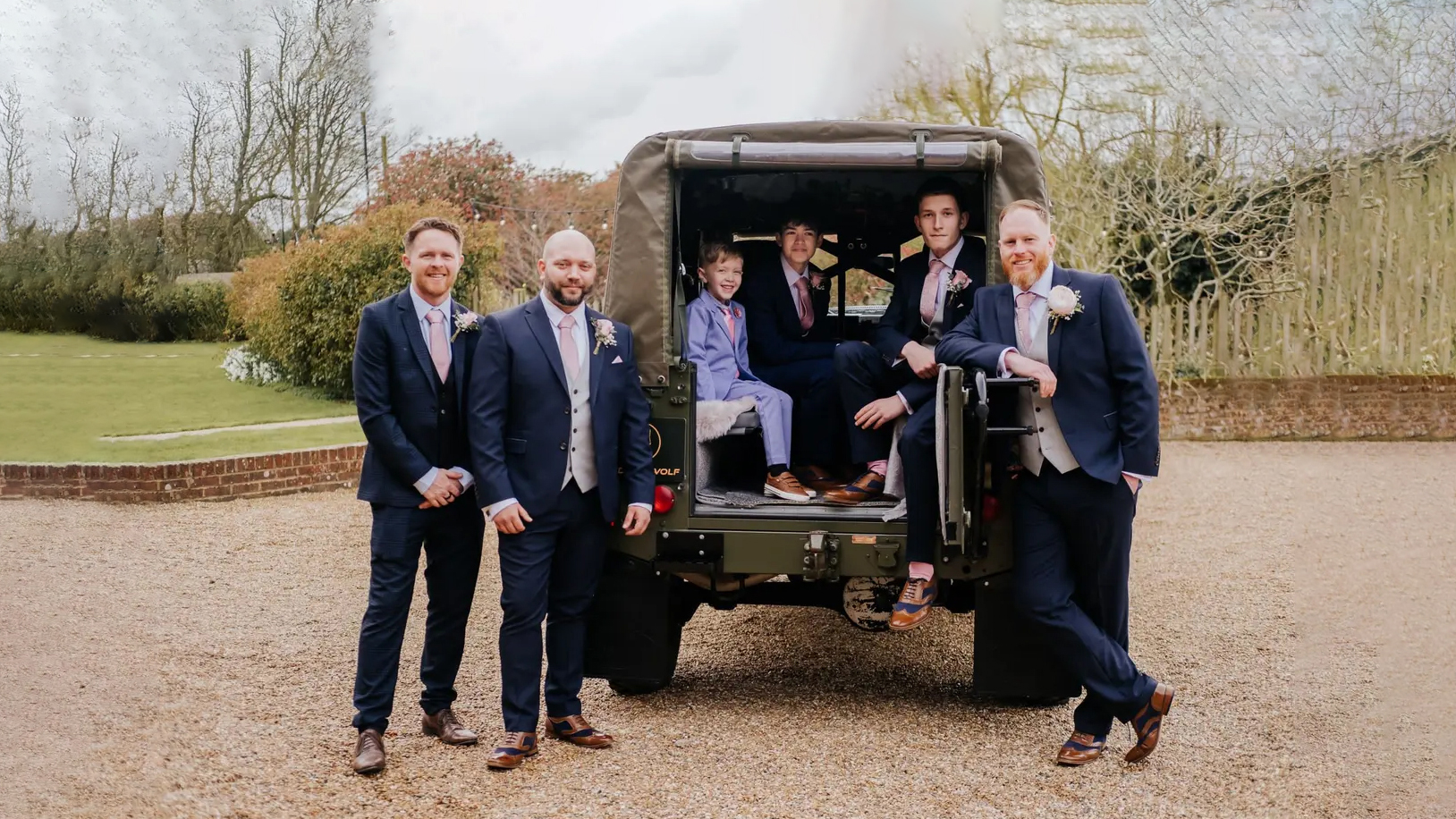 Army green Landrover with Groom, Bestmen, usher and Page Boy standing around the vehicle