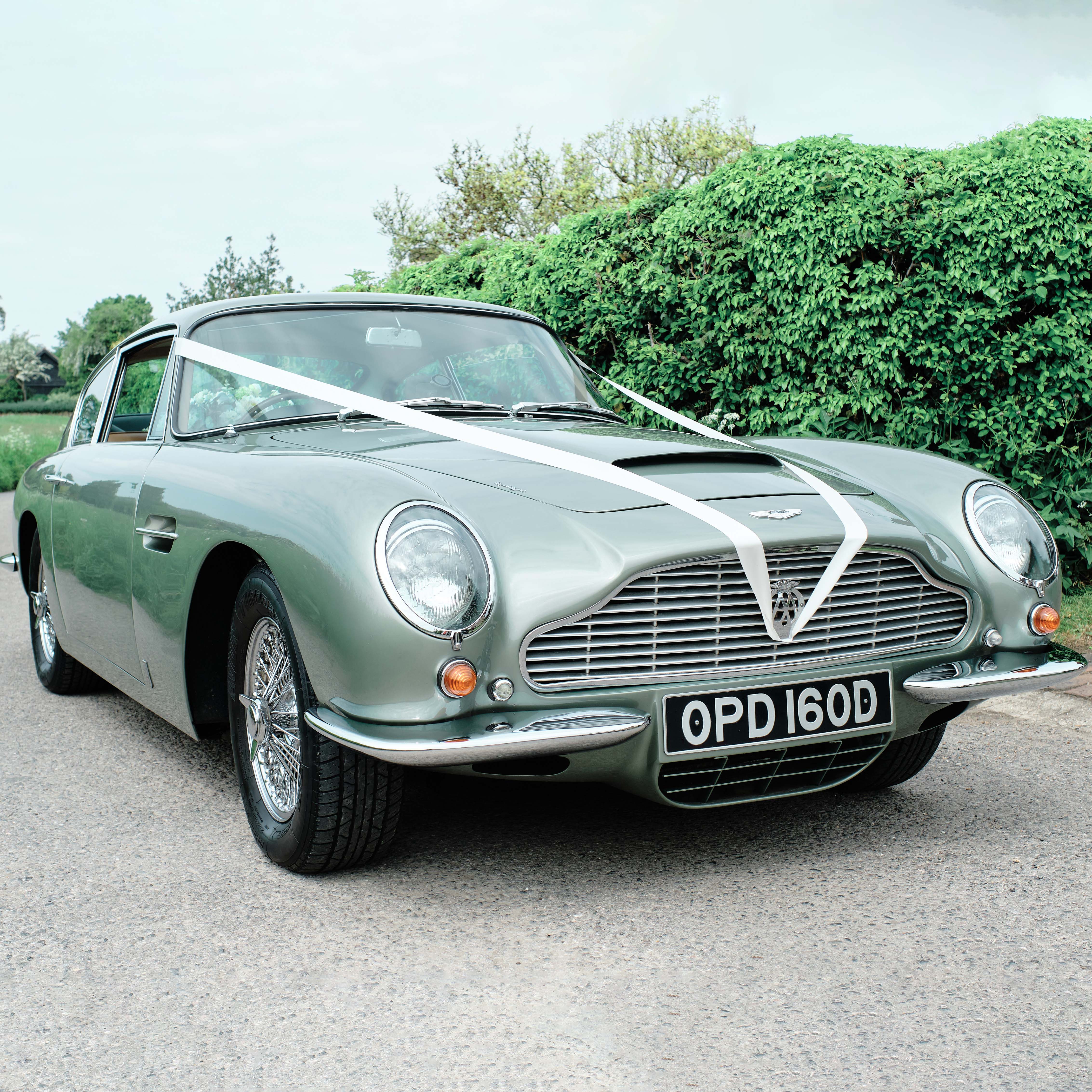 Classic Aston Martin DB6 in Metallic Green decorated with white ribbons.