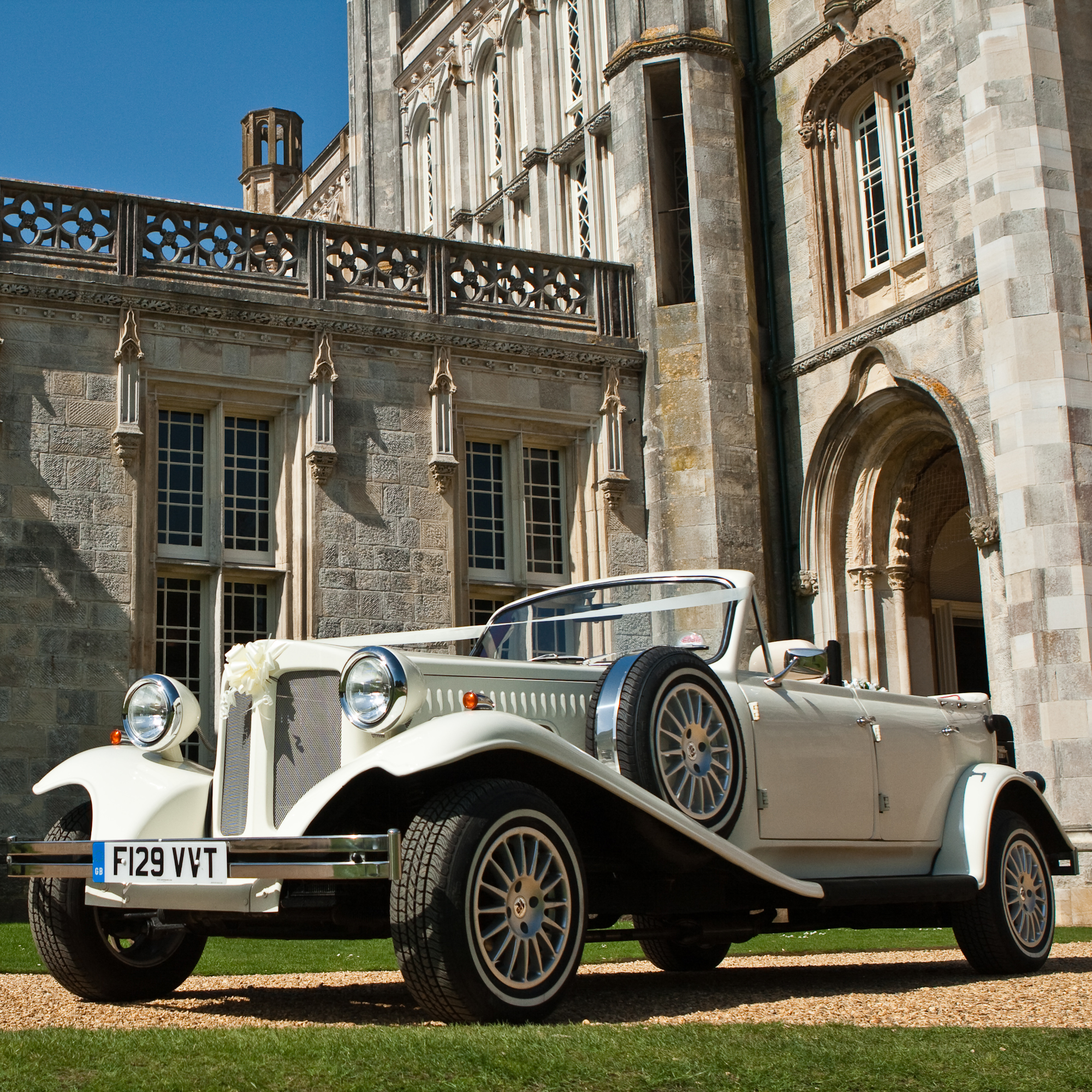 1930s Style Vintage Beauford Convertible in White with roof down and spare wheel mounted on the side.