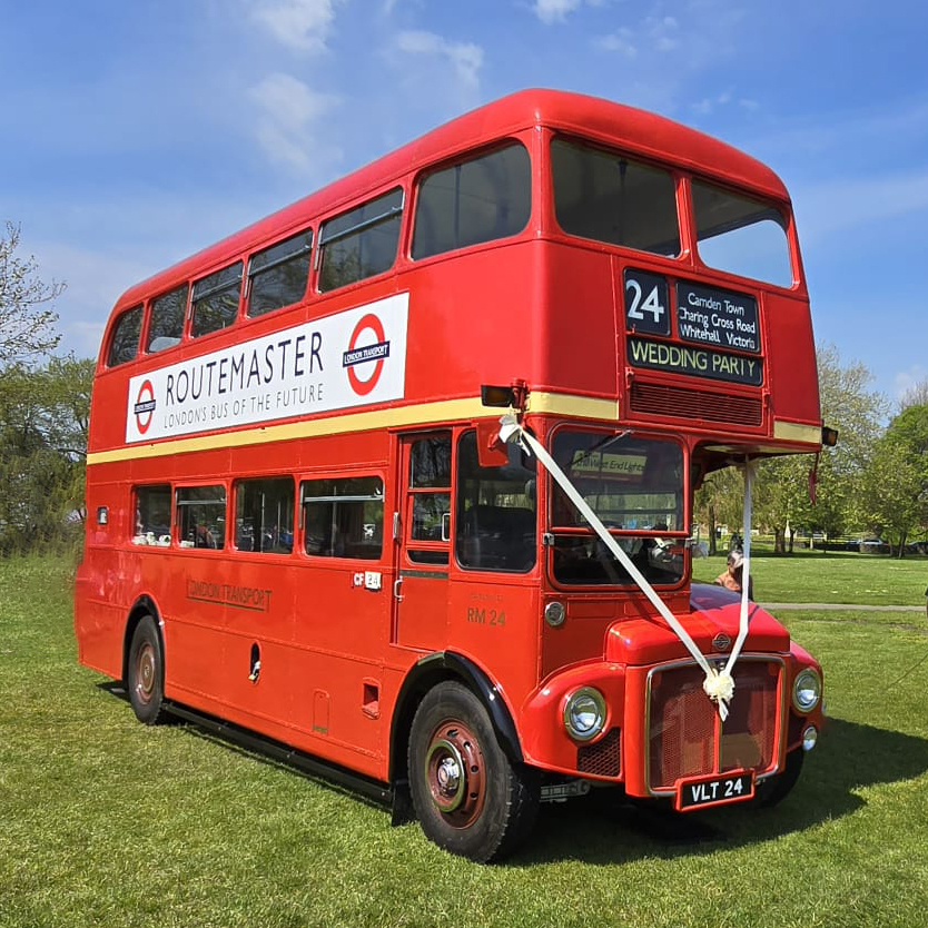 Double Decker Red Routemaster Bus decorated with white ribbons and vintage advertising on the side.