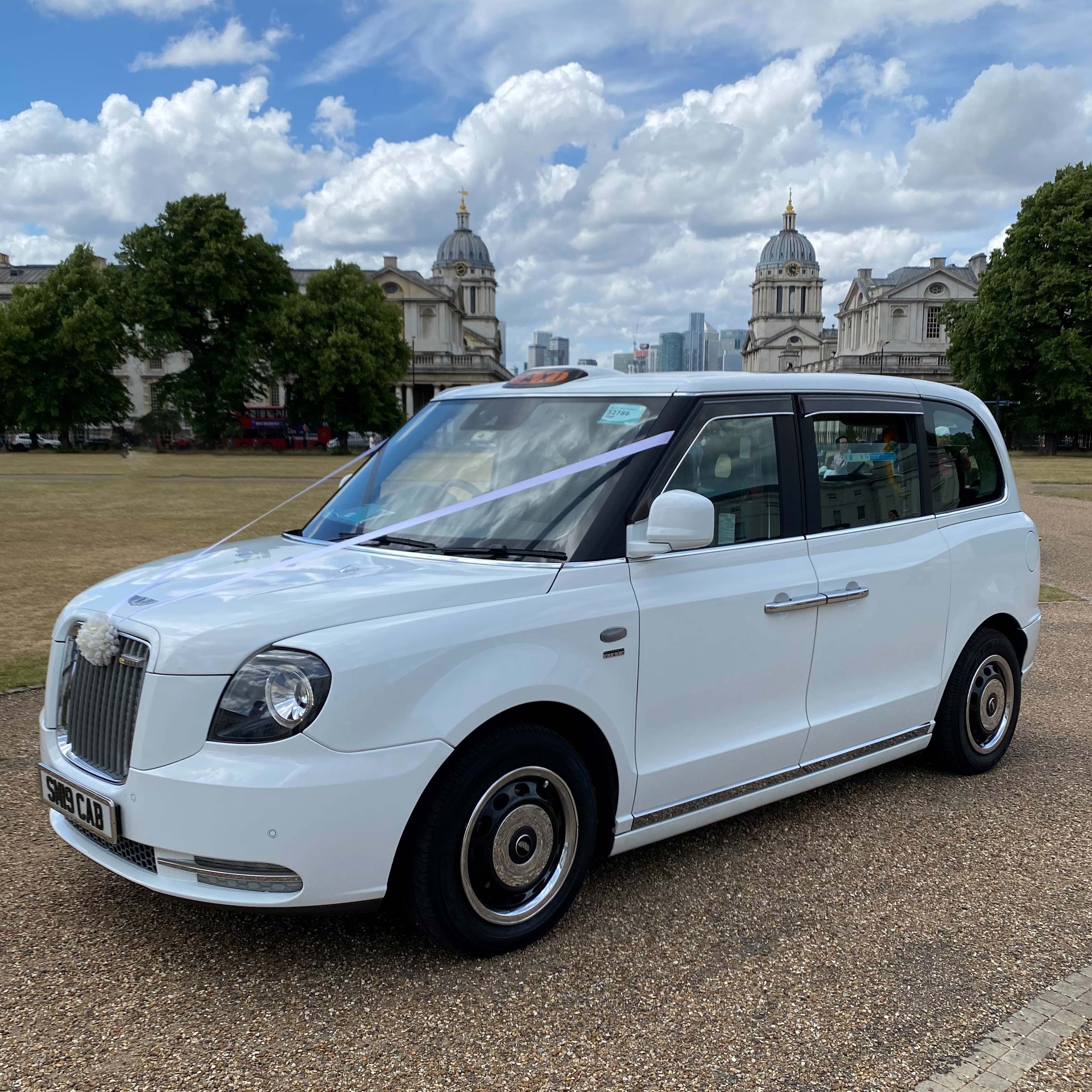Fully electric White Taxi Cab decorated with ivory ribbons and bow on its front grill.