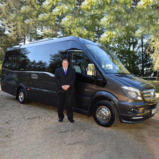 16-seater Mercedes Sprinter Bus in Grey with chauffeur standing in front of the bus.