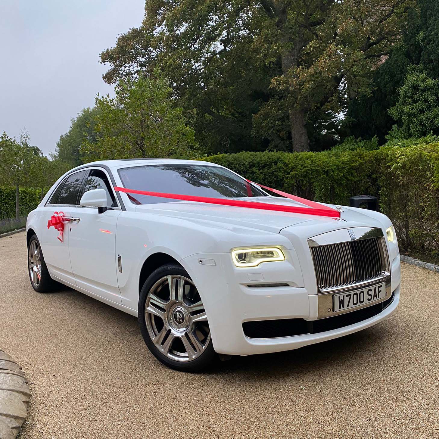 White Rolls-Royce Ghost decorated with red ribbons and bows on door handles