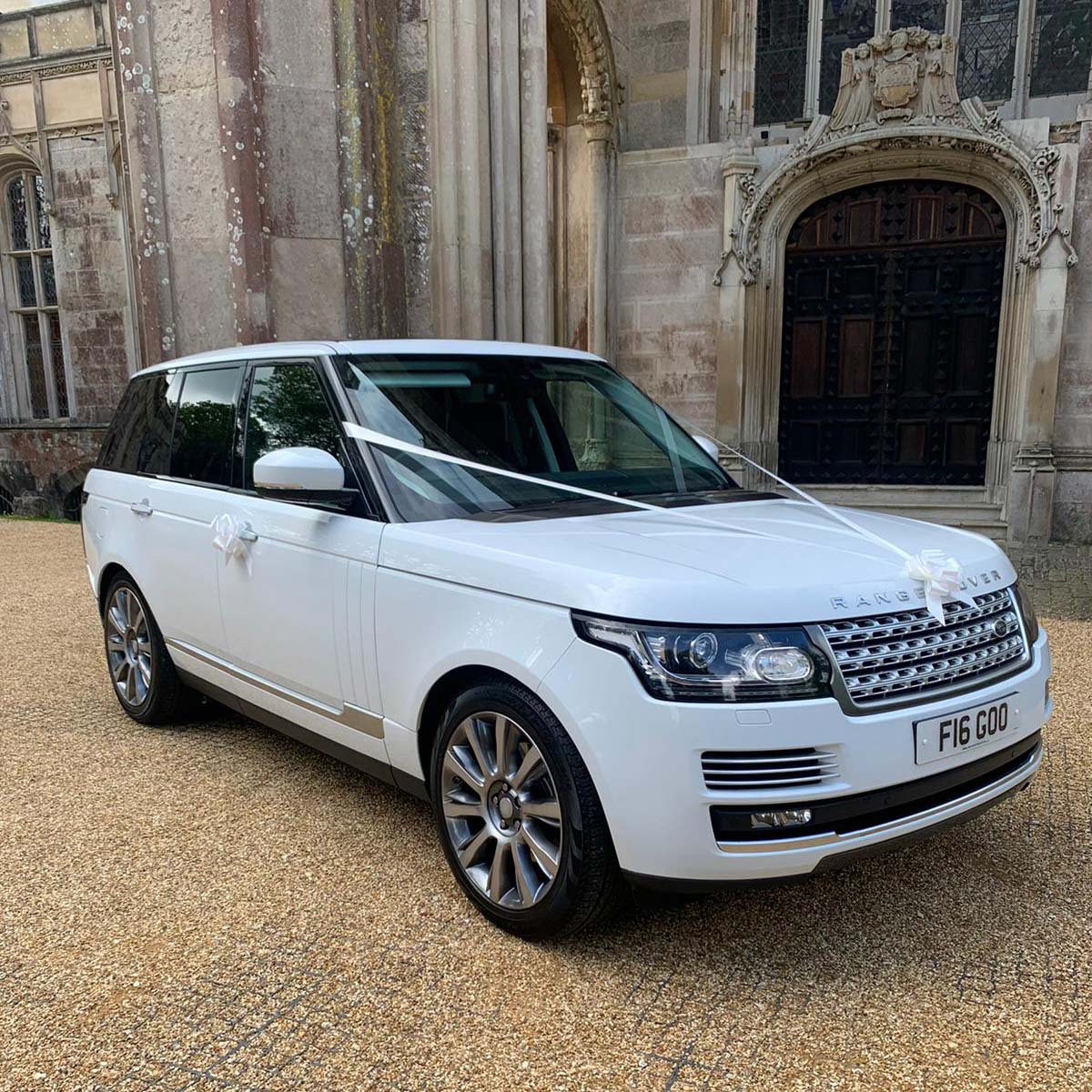 White Range Rover dressed with traditional white wedding ribbons.