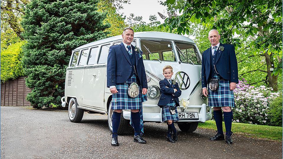 Classic VW Campervan with Groom, Groom's father and son standing in front of the vehicle in traditional Scottish wedding outfit. Blue Kilts with matching ties.