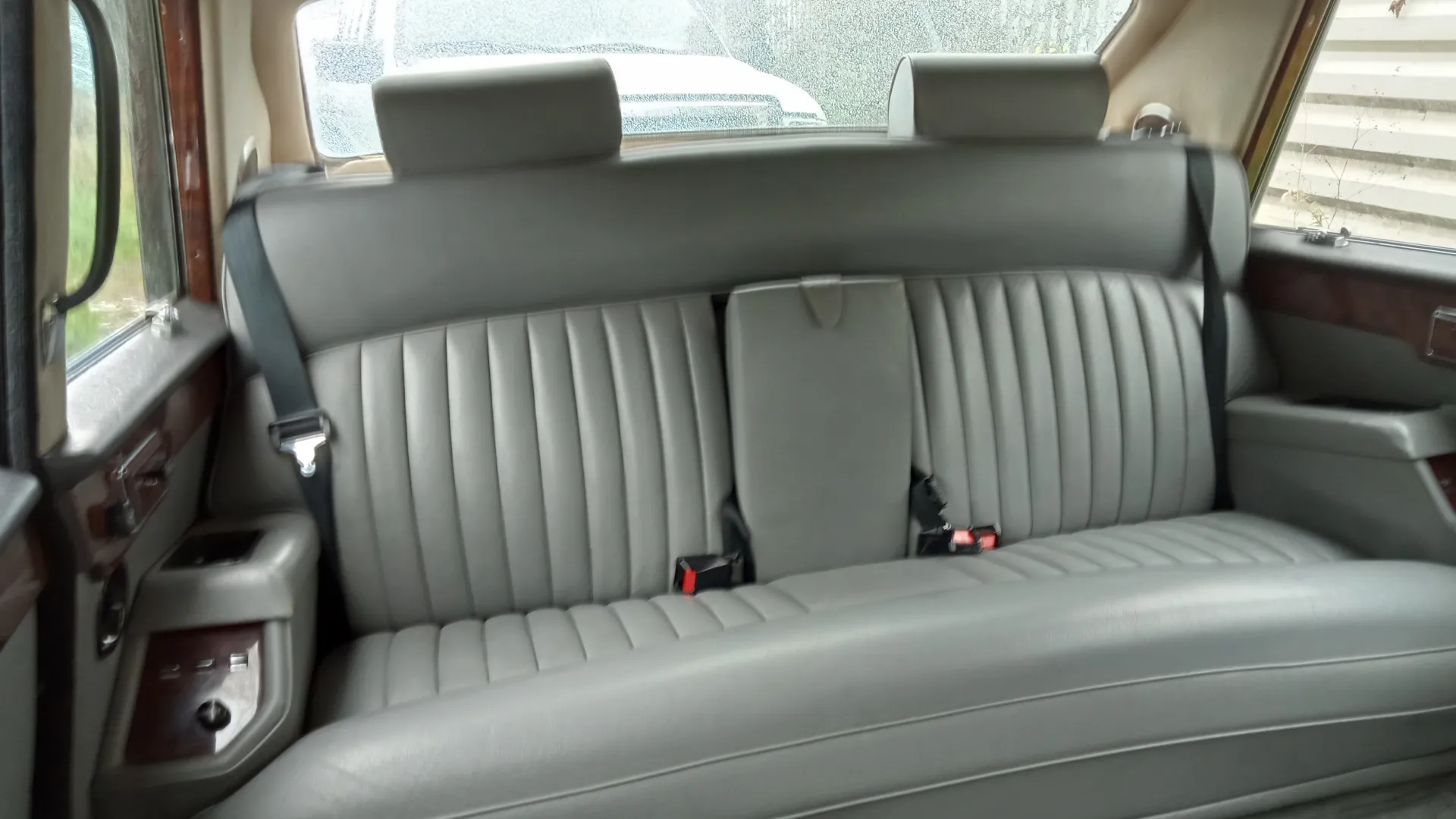 interior rear seating area in Silver leather showing two seat belts and wood on top of the door cards