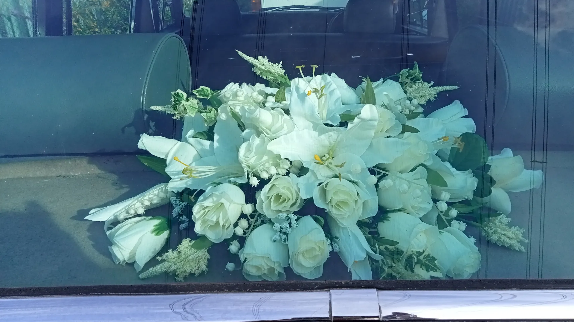 White posy flowers on the rear parcel shelf of Daimler. photo taken through the rear window.