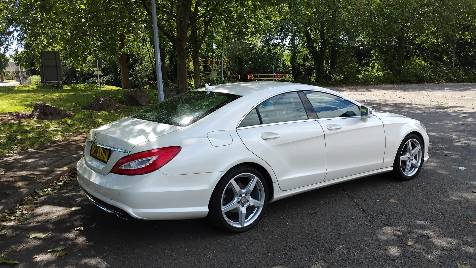 Rear side view of White Mercedes CLA AMG with Green Trees in the background