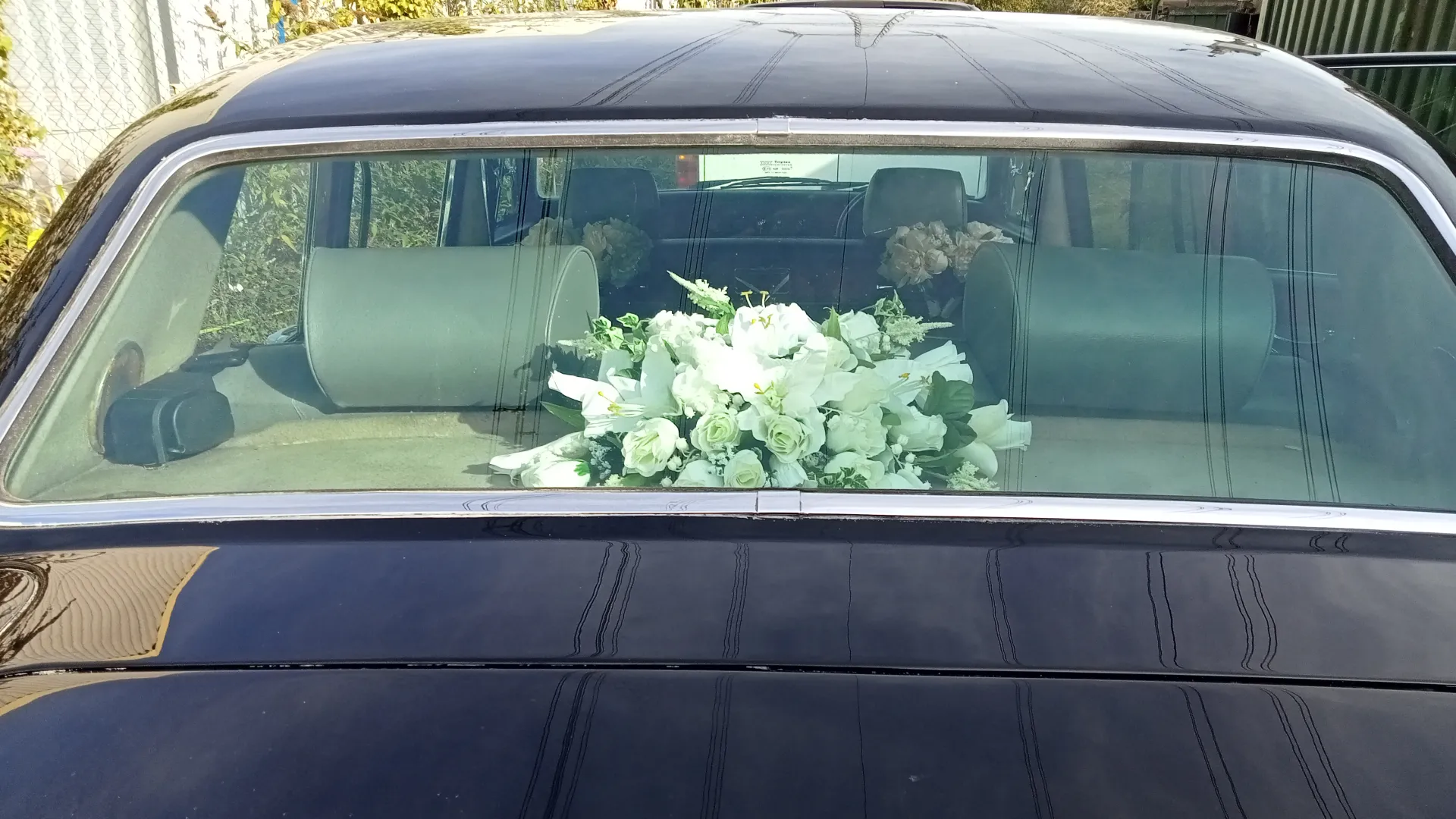 White posyu of flowers on the rear parcel shelf of Black Daimler limousine