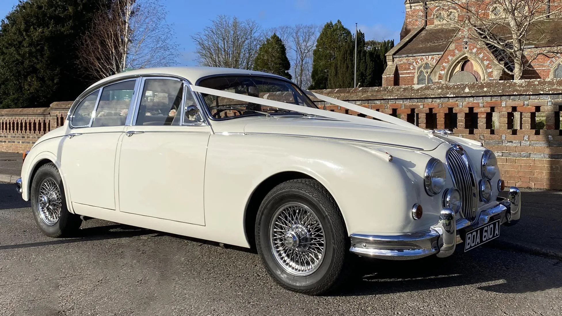 Classic Old English White Jaguar Mk2 decorated with White ribbons in front of a church in Lewes.