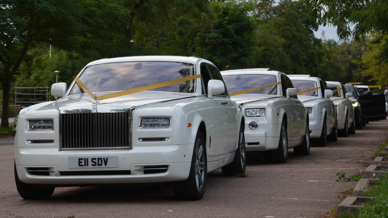 Fleet of White Rolls-Royce Phantom in the street of London with Matching Gold Ribbons