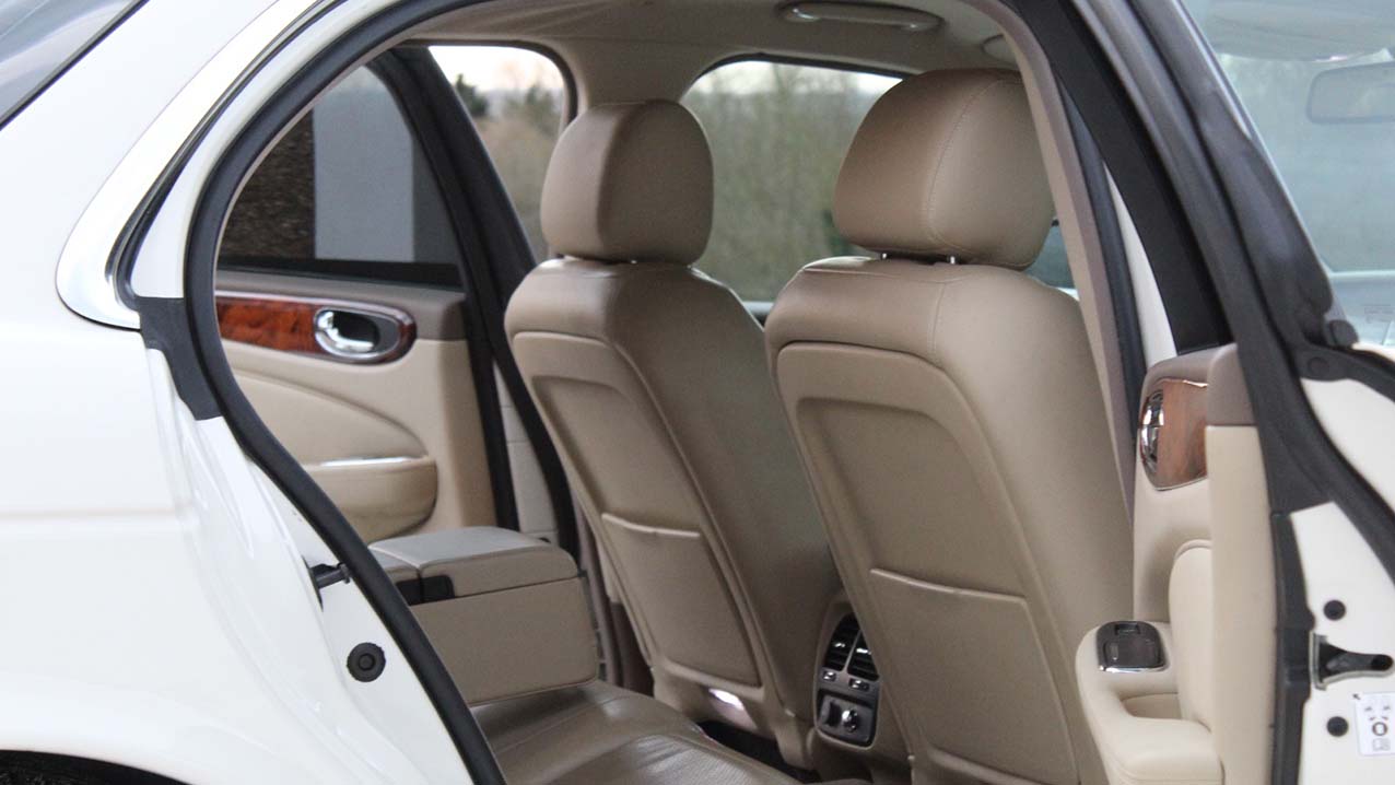 Rear interior view of White Jaguar XJ showing cream leather interior and large legroom