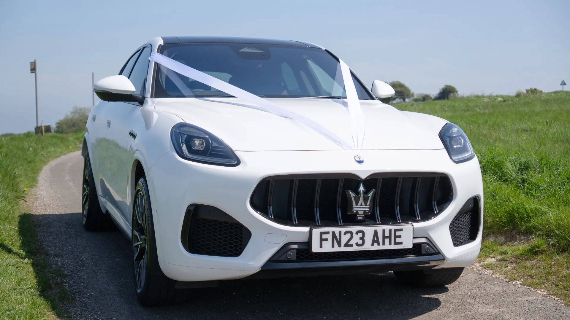 Front view of White Maserati Grecale decorated with white ribbons accross its front bonnet