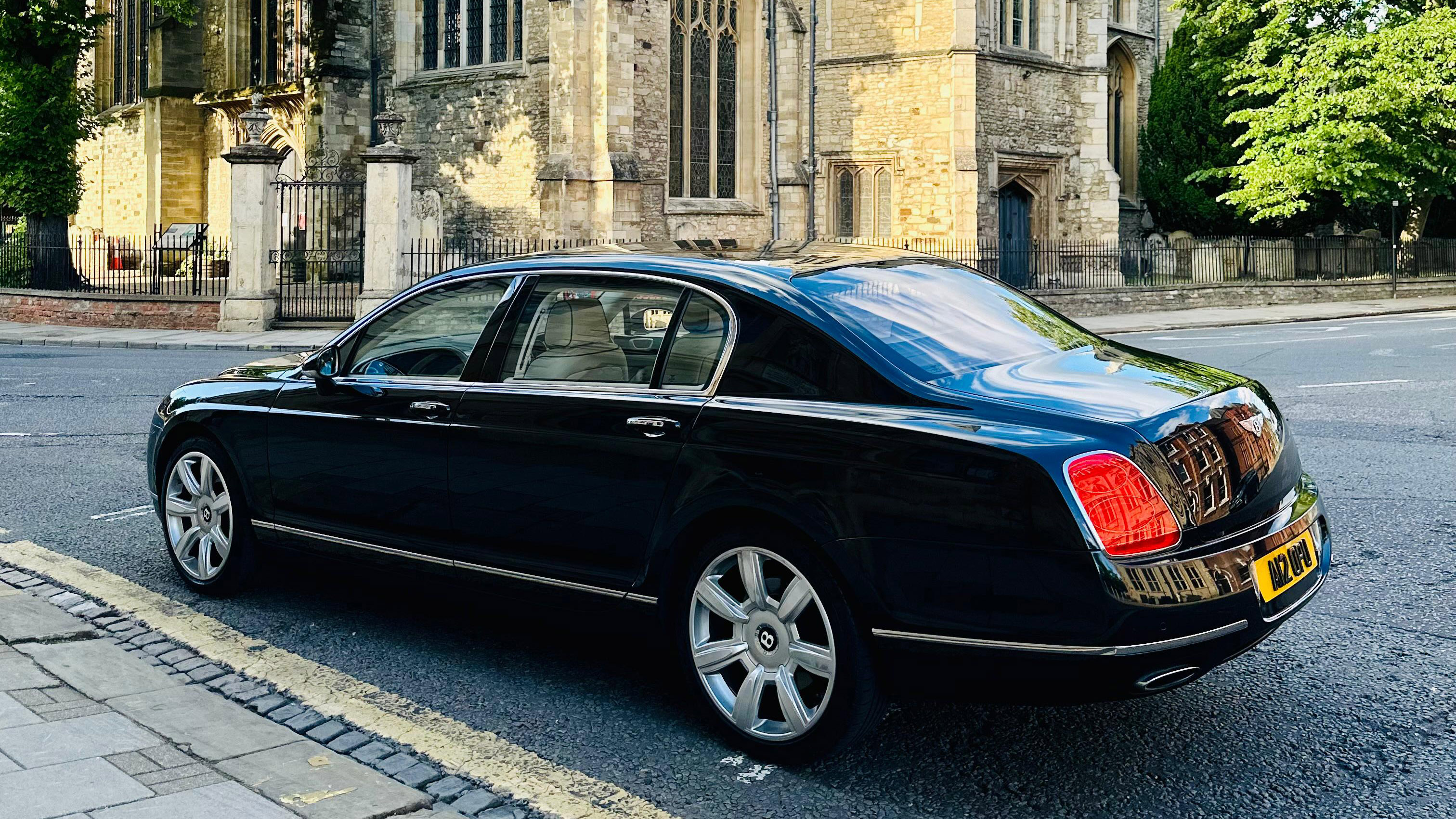 Rear Left view of black Bentley Mulsanne parked on the street with view of a church in the background