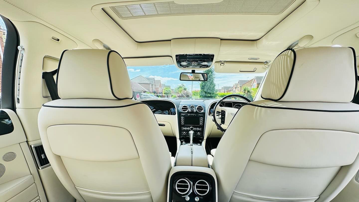 INterior photo taken from the rear seat looking forward into the driver's seat, Sinroof is closed, Cream leather seats and black dashboard