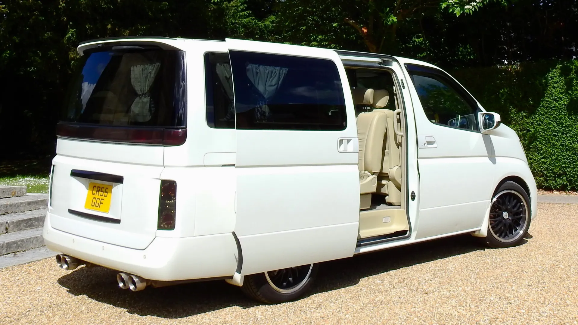 Right rear view of White Nissan Elgrand with rear passenger door open. Black Alloy wheels.