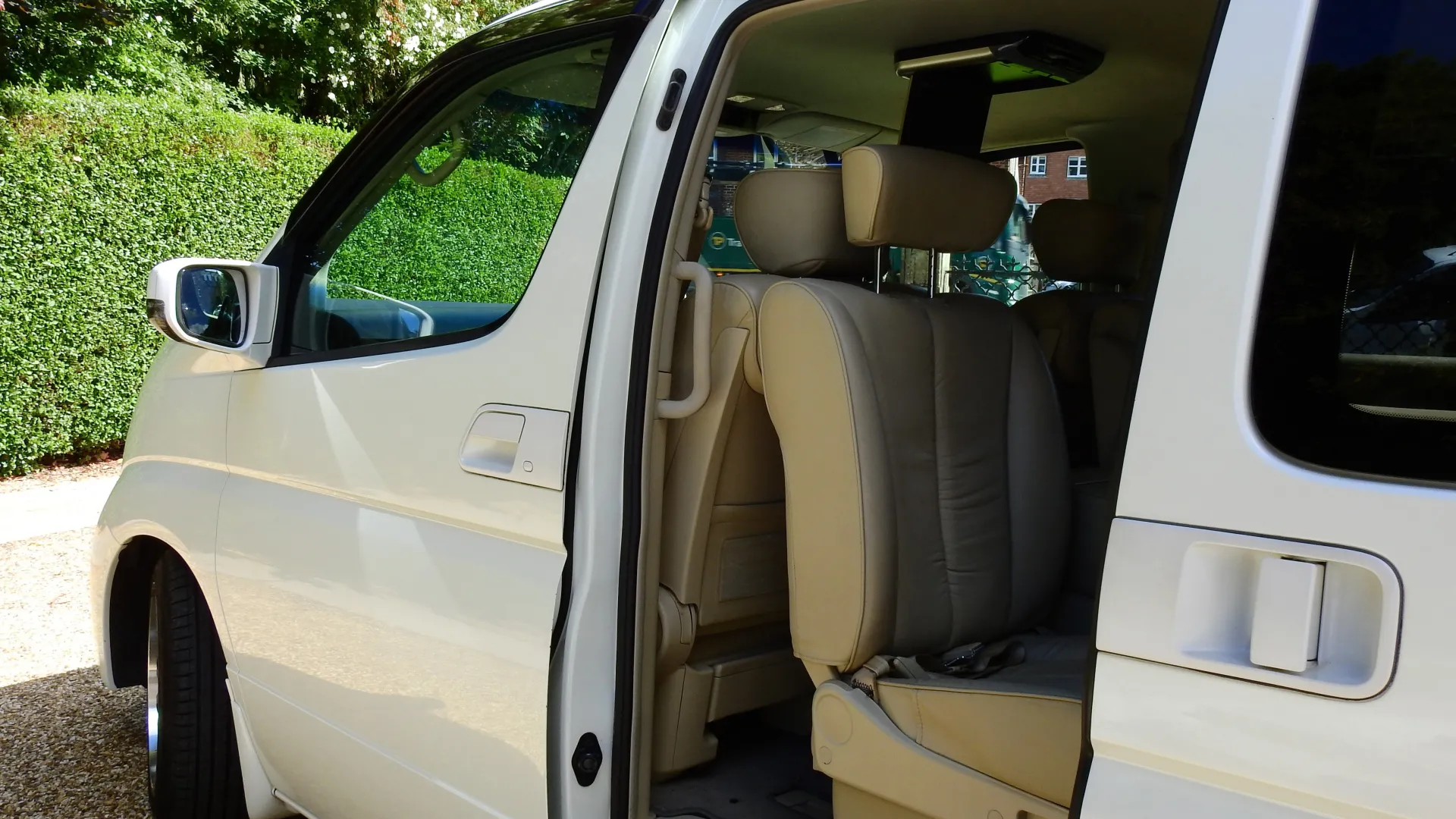 Close up view of White Nissan Elgrand with rear passenger door open showing cream leather interior