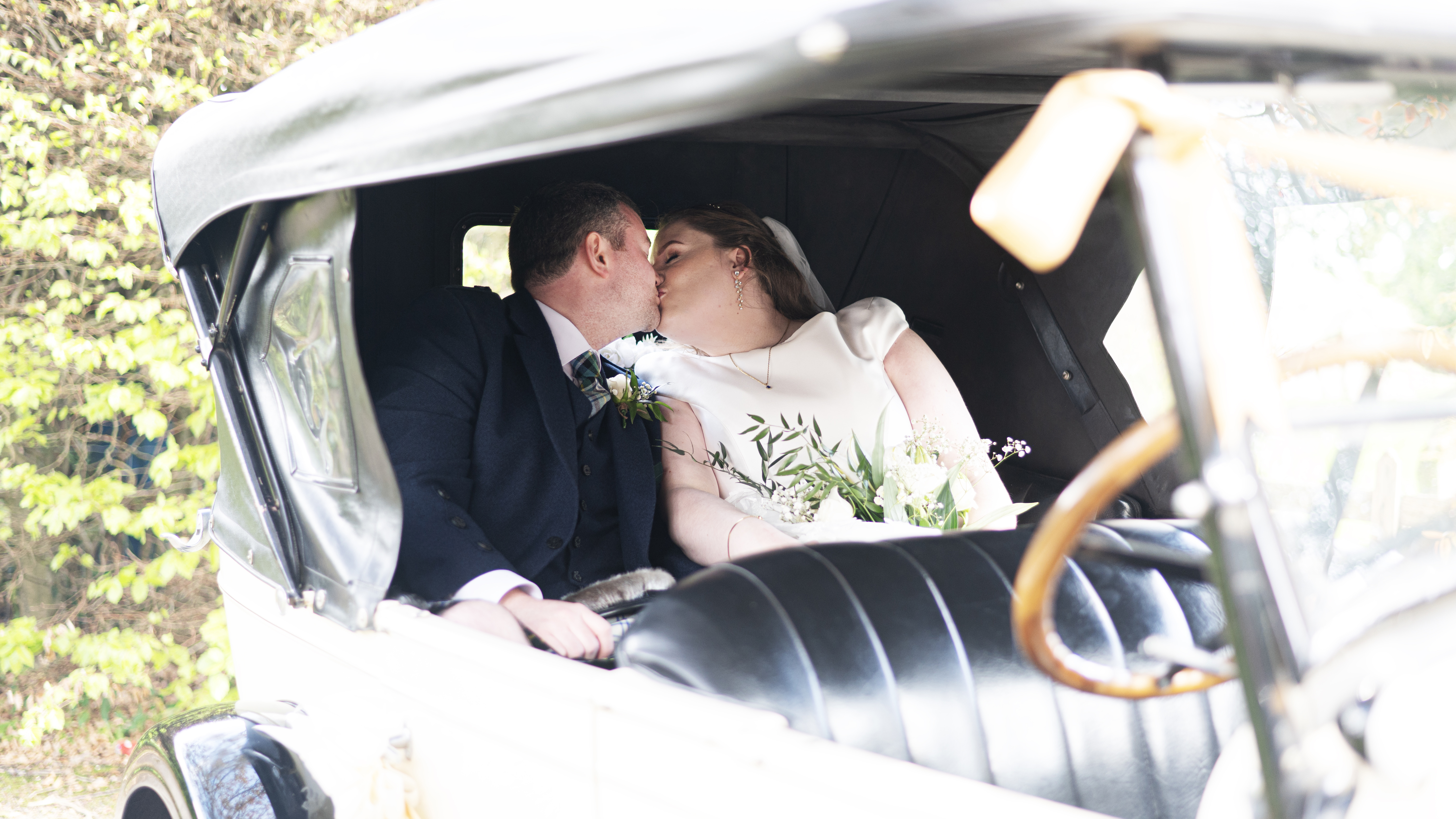 Bride and Groom kissing in the back of the vintage car