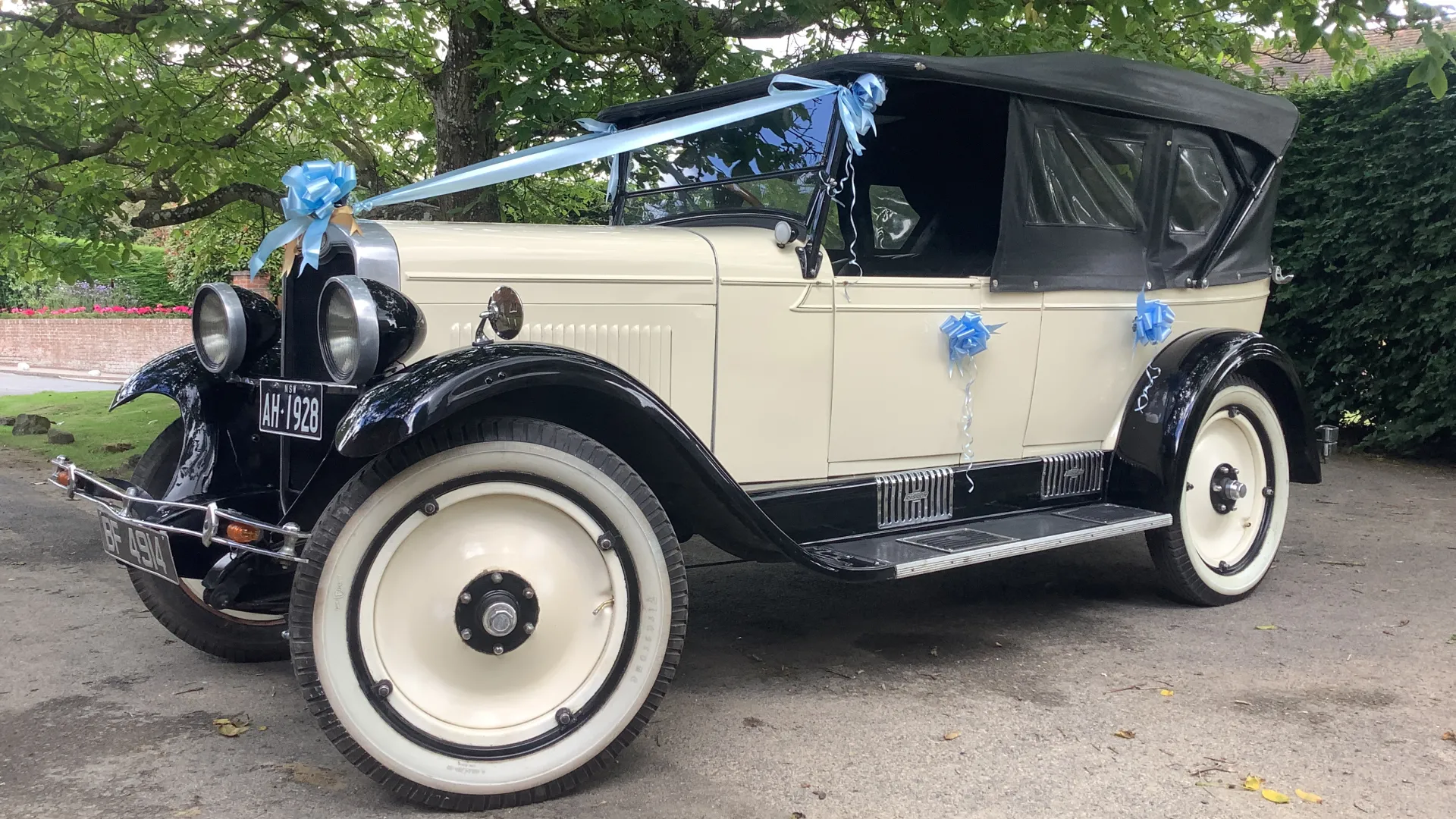 Left view of Vintage Chevrolet in ivory with plain ivory wheels decorated with baby blue ribbons and bow