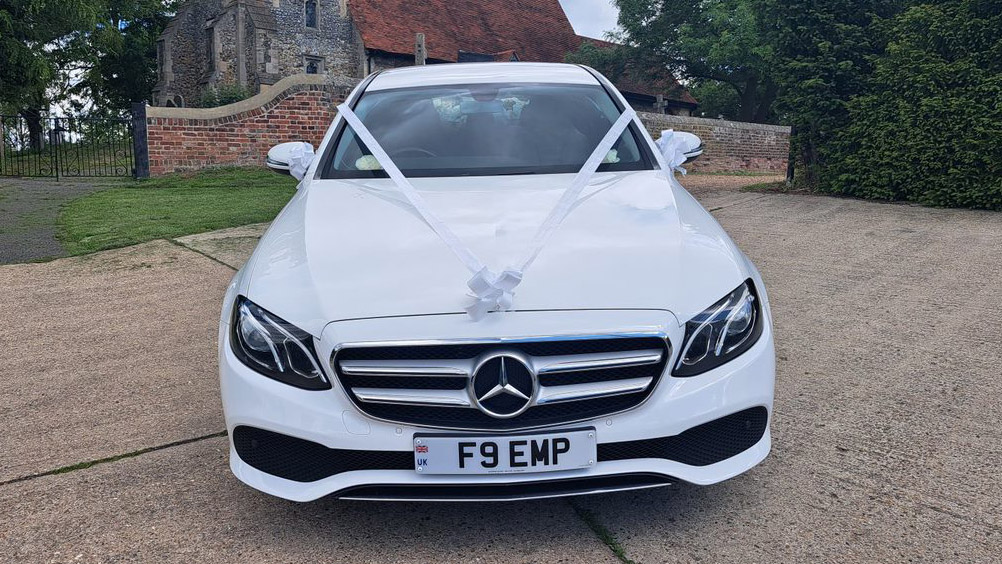 Front view of Mercedes in white decorated with white ribbons in front of a church