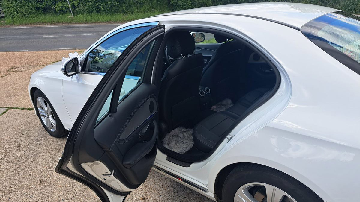Left side rear passenger seating with door open showing black leather seats