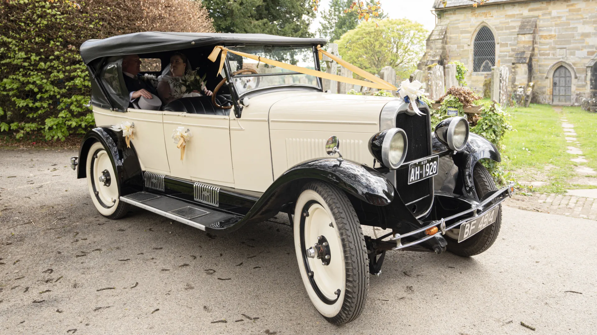 Right side view of Vintage Chevrolet with couple seating in the rear passengers seats. Car is decorated with Gold Ribbons