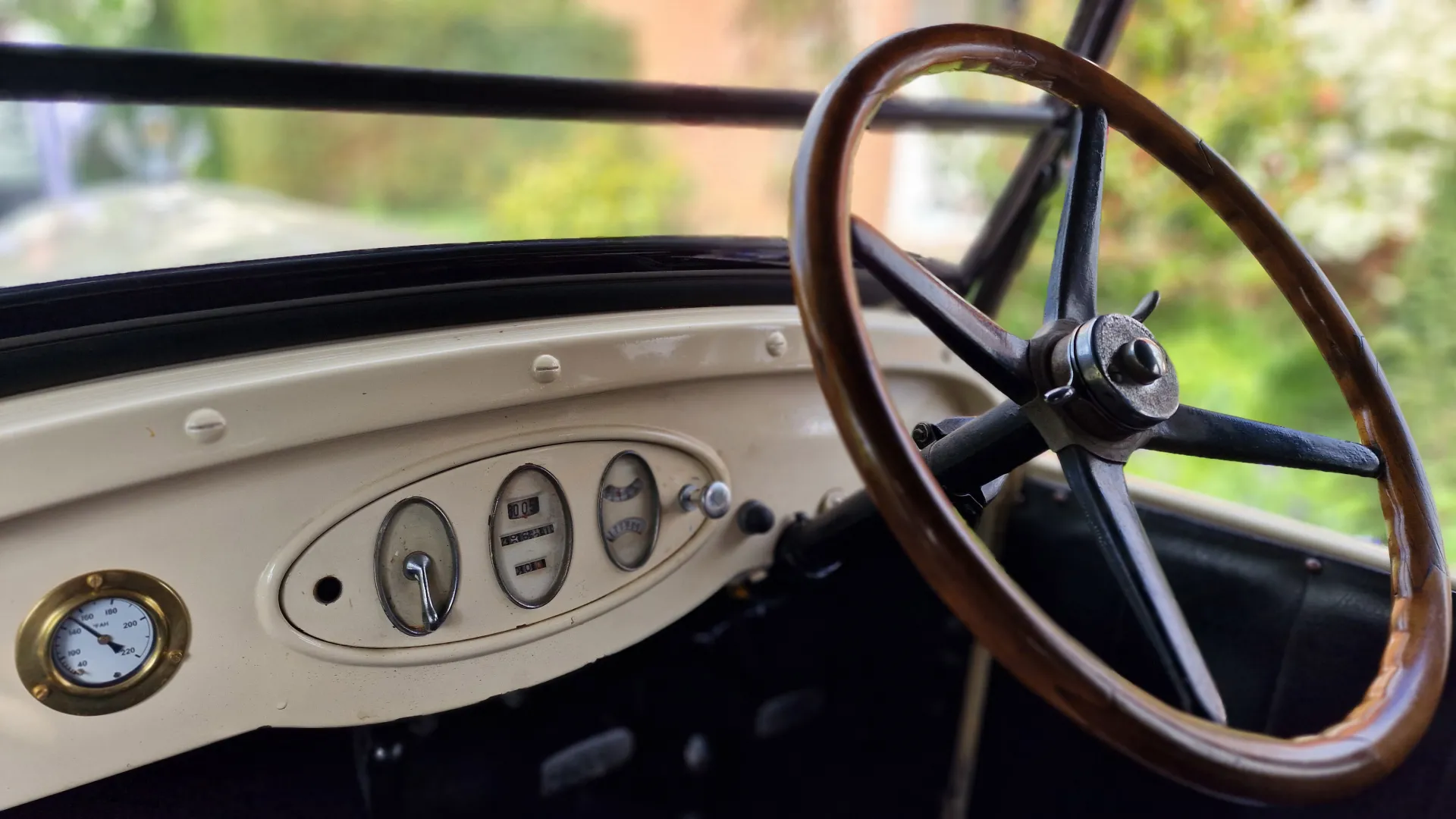 Driver's wodden steering wheel and ivory coloured dashboard