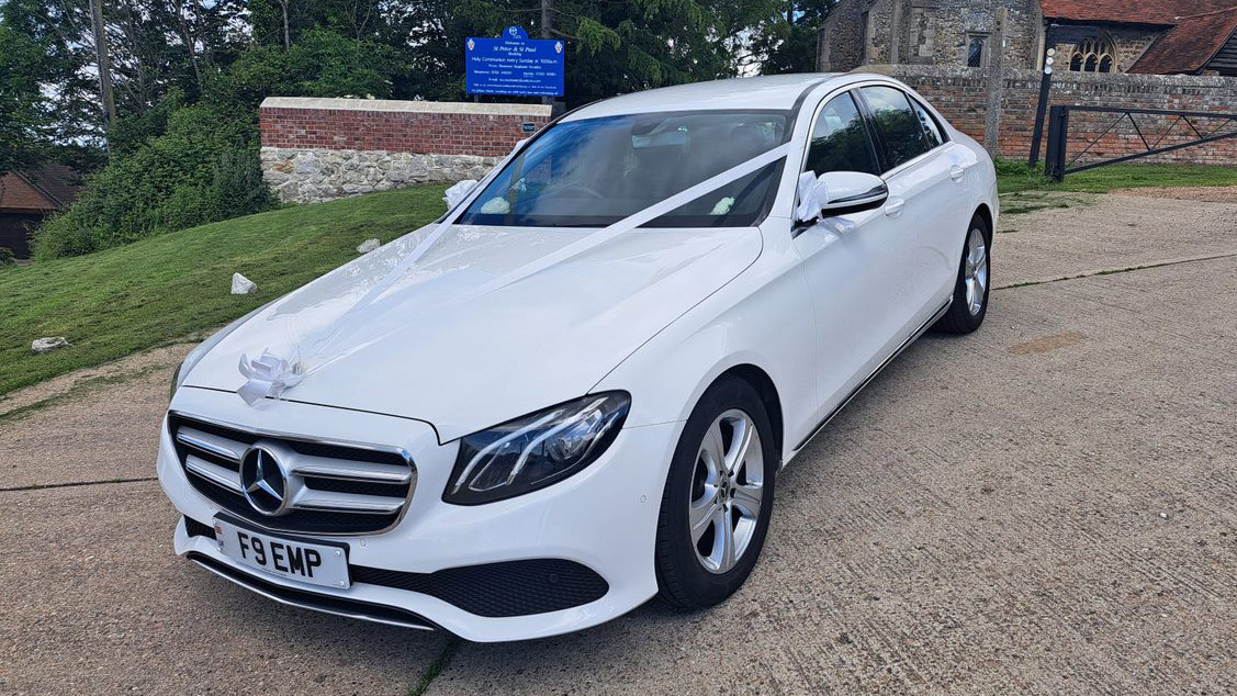 Left front view of white mercedes dressed with white ribbons in front of a church in Essex