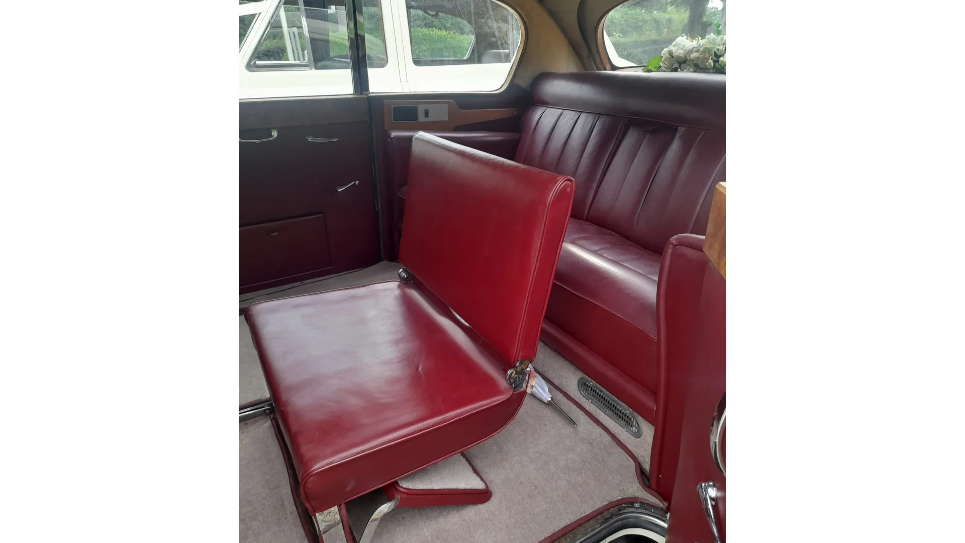 Rear interior cabin inside Austin Princess with Cream carpet and Burgundy Seat showing the casual seat raised up for additional passenger seating