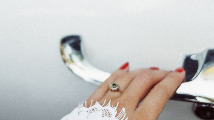 Bride wearing a wedding ring opening the door of the classic cadillac with chrome door handle.