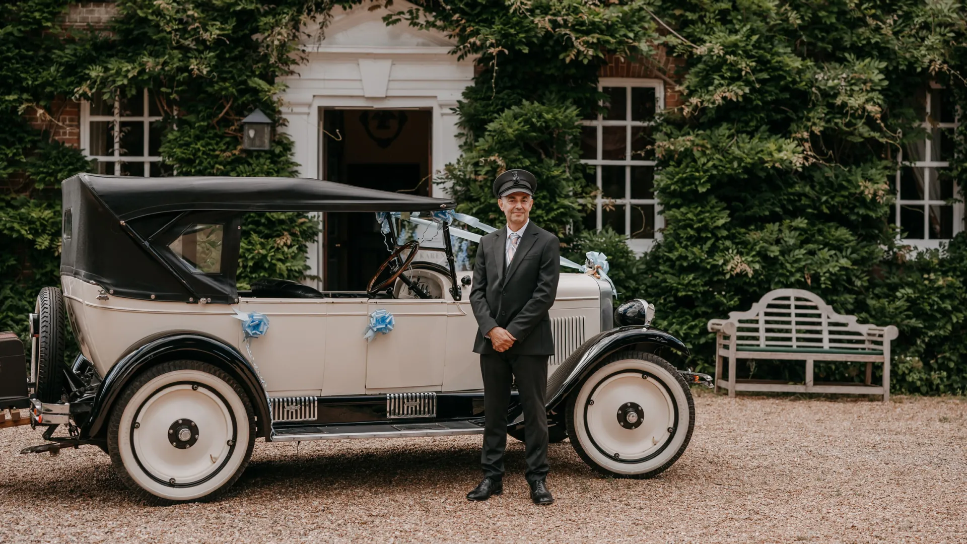 Chauffeur standin in front of an Ivory Vintgae Chevrolet wedding car