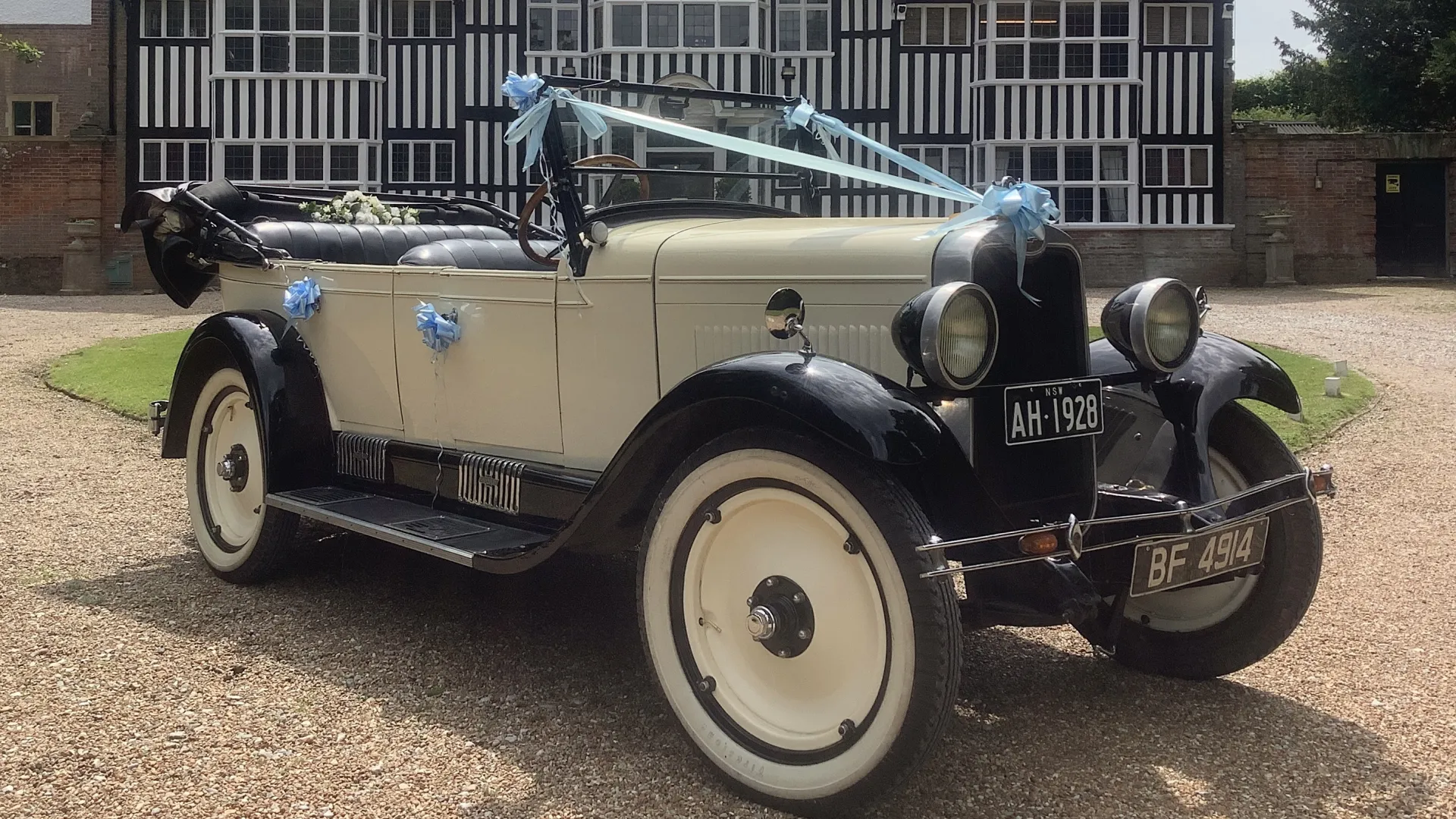 Right side view of Ivory vintage Chevrolet with light blue ribbons and convertible roof down