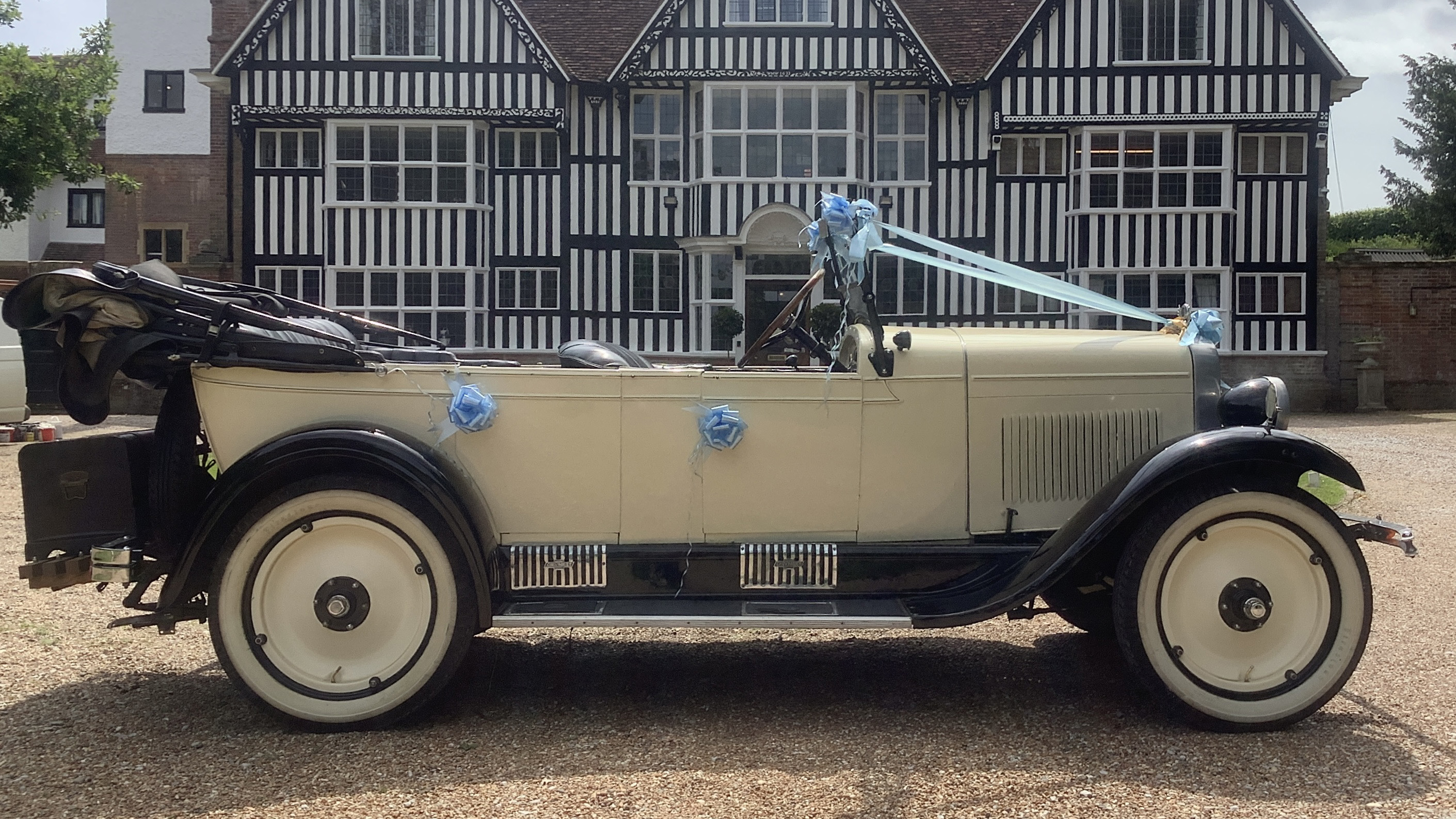 Full Right side view of vintgae american car with convertible roof down and decorated with blue ribbons